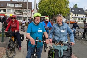 Julia Retzlaff mit Fahrrad und weiteren Radfahrenden bei einem Stopp während der Tour in Querum, Essener Straße