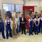Gruppenbild: Julia Retzlaff, Annette Schütze und Hubertus Heil stehen zwischen einigen jungen Männern in blauer Arbeitskleidung