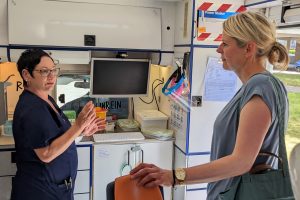 Angela McLeod erklärt Julia Retzlaff die mobile Zahnarztprxis, beide stehen im umgebauten Rettungswagen am Behandlungsstuhl.