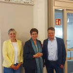 Auf dem Bild haben sich Julia Retzlaff, Birgit Hone und Christoph Bratmann zusammen aufgestellt, um sich fotografieren zu lassen. Sie stehen in einem Flur im Rathaus.