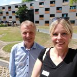 Julia Retzlaff und ein Mann vom Diakonieheim stehen vor dem Diakonieheim in der Sonne