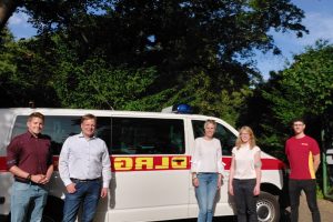 JUlia Retzlaff, Christoph Bratmann und drei Vertreter:innen der DLRG Ortsgruppe Braunschweig vor einem Einsatzwagen