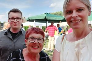 Ein Selfie (Aufnahme, bei der die fotografierende Person die Kamera auf sich selbst hält) von Julia Retzlaff mit einer Frau vom Verein und einem jungen SPD-Genossen. Im Hintergrund ein Garten mit Sonnenschirmen