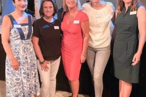 Vor einer professionell beleuchteten Bühne im Innenraum des Lokparks Braunschweig stehen Julia Ratzlaff und vier weitere Frauen