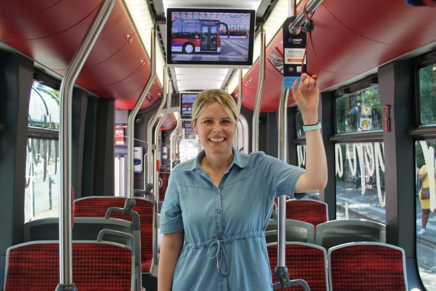Julia Retzlaff steht im Gang einer Straßenbahn und hält sich an einer Halteschlaufe fest.