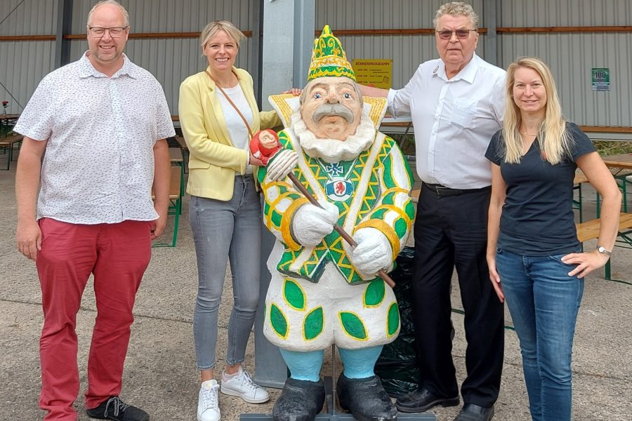 Ein Gruppenbild auf dem Geländer des Schoduvel-Zentrums. Um eine menschengroße Karnevalsfigur herum stehen auf der einen Seite Jörn Domeier und Julia Retzlaff, auf der anderen zwei Karnevalist:innen