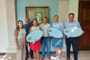 Julia Retzlaff steht mit Christoph Bratmm und Annette Schütze in einem Altbaugebäude auf einem Flur. Mit ihnen zusammen stehen drei Vertreter:innen der Arbeitnehmendenvertretungen VHS und NBW. Die drei Landtagskandidierenden halten große Sprechblasen aus Papier in den Händen, auf denen sie ihre Ansätze zu den Themen Aus- und Weiterbildung von Erwachsenen festgehalten haben