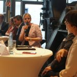Julia Retzlaff sitzt an einem Stehtisch und moderiert. Während sie ins Mikrofon spricht, beobachtet SPD-Parteivorsitzende Saskia Esken sie konzentriert.